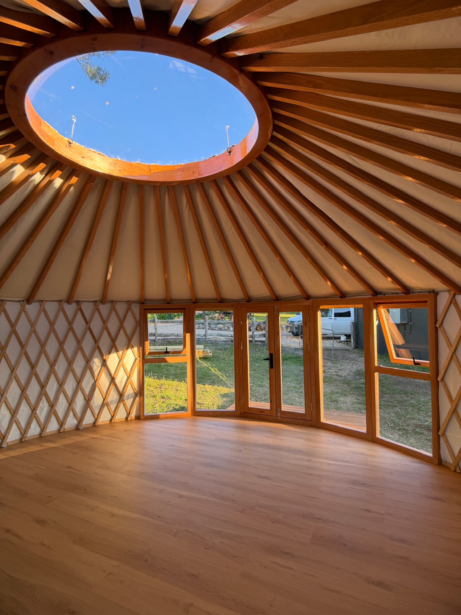 Yurt interior with dome skylight and window wall, suited to a bedroom or guest space